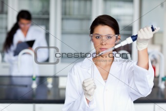Serious female scientist pouring a liquid in a tube