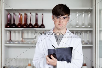 Male science student writing on a clipboard