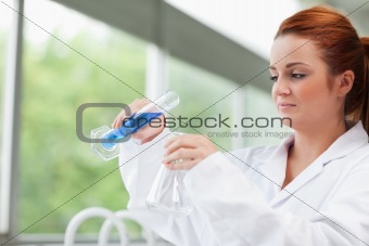 Science student pouring liquid in an Erlenmeyer flask