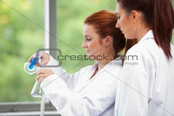 Young scientists pouring liquid in an Erlenmeyer flask