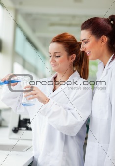 Portrait of scientists pouring liquid in an Erlenmeyer flask