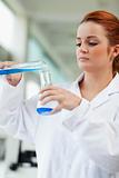 Portrait of a scientist pouring blue liquid in an Erlenmeyer flask