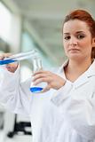 Portrait of a cute scientist pouring blue liquid in an Erlenmeyer flask