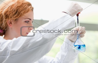 Science student putting blue drops in a liquid