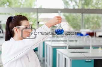 Brunette scientist looking at a flask