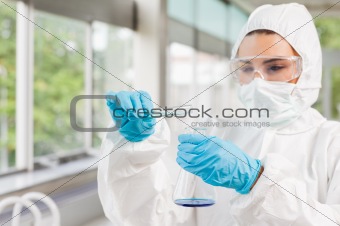 Protected female scientist pouring liquid