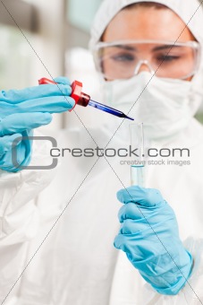 Portrait of a protected scientist dropping a liquid in a test tube