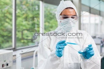 Protected science student dropping blue liquid in a Petri dish