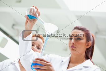 Scientist emptying a flask into another one