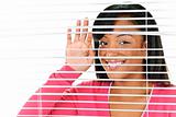 Smiling woman looking through blinds