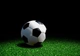 Soccer ball on grass over black background
