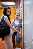 Portrait of student opening her locker while speaking with her friend