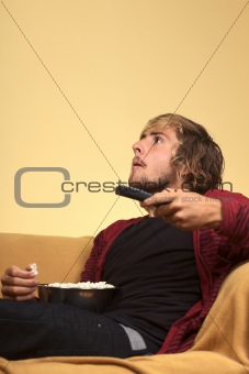 Young Man Watching TV and Eating Popcorn