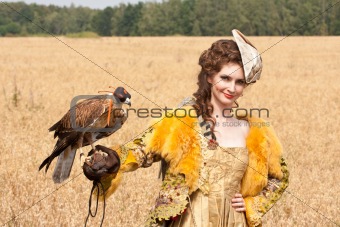 The woman in a beautiful old style dress with falcon has a rest 