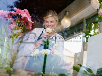 Blonde girl working in flowers shop with roses and gerbera