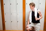 Handsome young sports student leaning on a locker