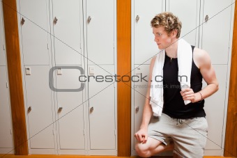 Handsome young sports student leaning on a locker