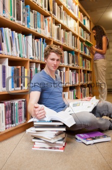Portrait of a student doing research while his classmate is reading