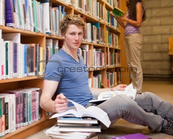 Male student doing research while his classmate is reading