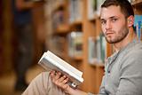 Serious male student holding a book