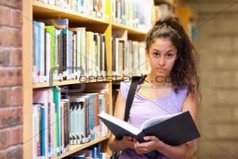 Serious female student holding a book