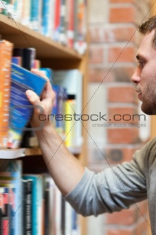 Portrait of a male student picking a book