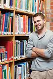 Portrait of a smiling male student leaning on a shelf
