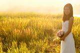 Asian bride at outdoor in a morning surrounding by golden sunlig