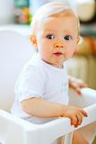 Eat smeared pretty baby in baby chair interestedly looking

