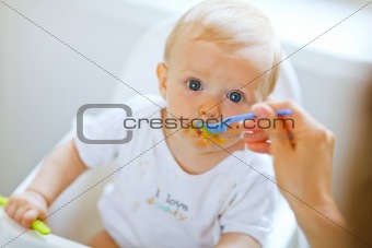 Eat smeared pretty baby eating from spoon
