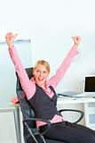 Happy business woman sitting at workplace rejoicing success
