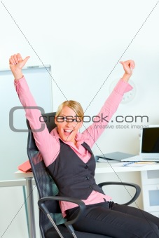 Happy business woman sitting at workplace rejoicing success
