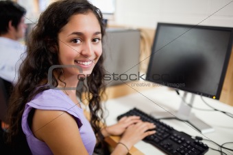 Smiling brunette student posing with a computer