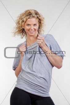 portrait of blond girl in gray shirt smiling - isolated on light gray