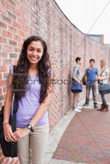 Portrait of a smiling student posing while her friends are talking
