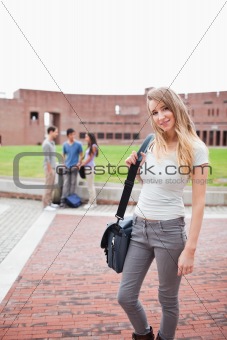 Blonde student posing while her friends are talking