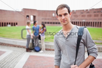 Serious student posing while his classmates are talking