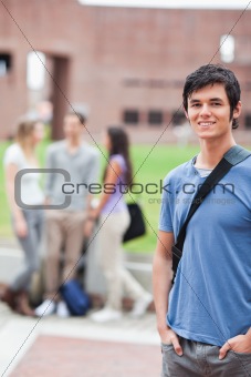Portrait of a handsome student posing while his classmates are talking