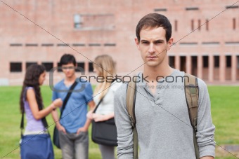 Lonely student posing while his classmates are talking