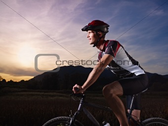 young man training on mountain bike at sunset