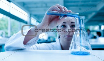 Scientist pouring a liquid in an Erlenmeyer flask with a test tube
