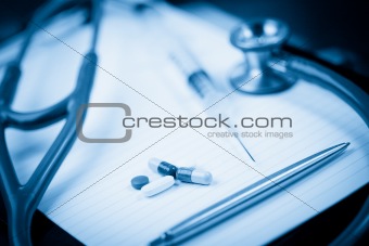 Note pad with stethoscope and pen along with  serynge and capsules