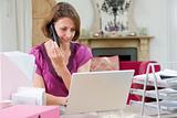 Woman using laptop and talking on phone