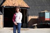 Farmer's Wife Standing In Front Of Farm Buildings