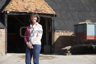 Farmer's Wife Standing In Front Of Farm Buildings