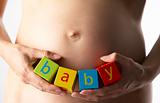 Pregnant Woman Holding Blocks Spelling "Baby"