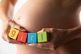 Pregnant Woman Holding Blocks Spelling "Girl"
