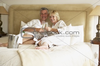 Middle Aged Couple Enjoying Champagne In Bedroom