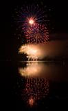 Colorful fireworks on black sky background with water reflection