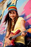 Beautiful brunette girl with guitar and graffiti wall at backgro